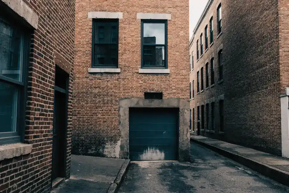 A ground-level garage door set into a pre-1930s brick row house, the type common on Hoboken's older blocks