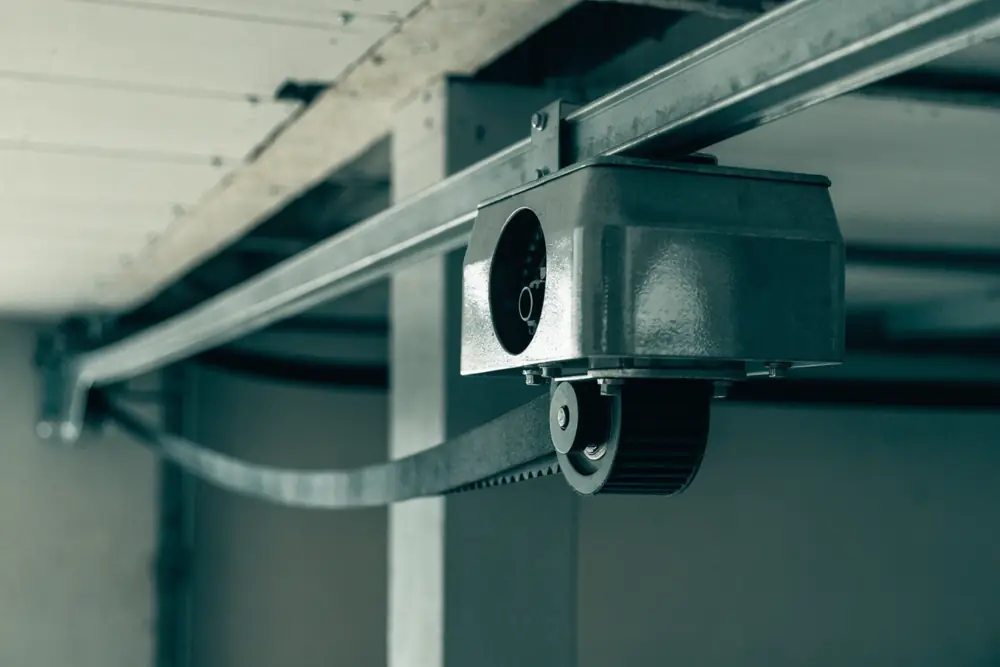 A belt-drive garage door opener motor head on its ceiling rail