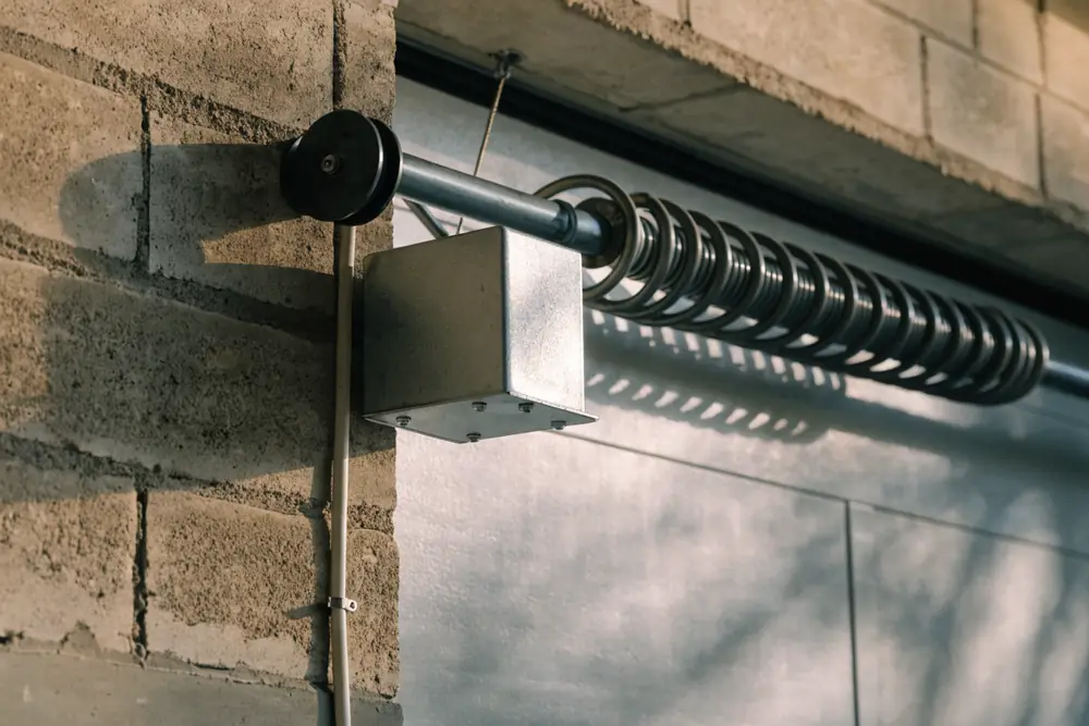 A wall-mounted garage door opener on the torsion shaft beside the door
